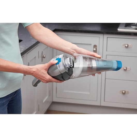 BLACKDECKER NVC215WA handstofzuiger met blauwe mondstuk in keuken vastgehouden.