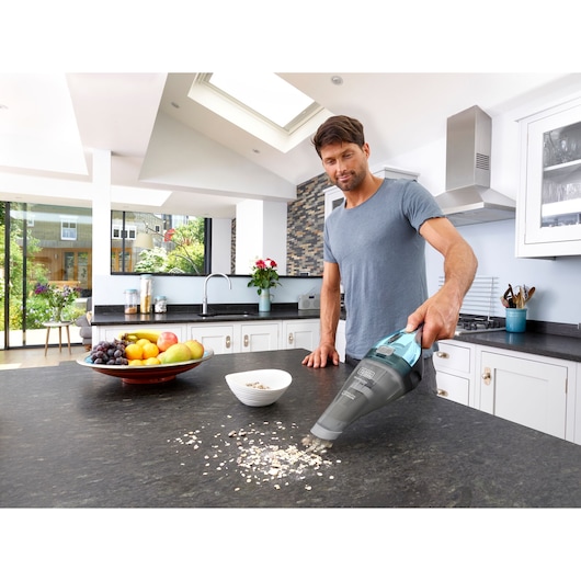 BLACKDECKER NVC220WBC handstofzuiger zuigt gemorste havermout van keukenblad.