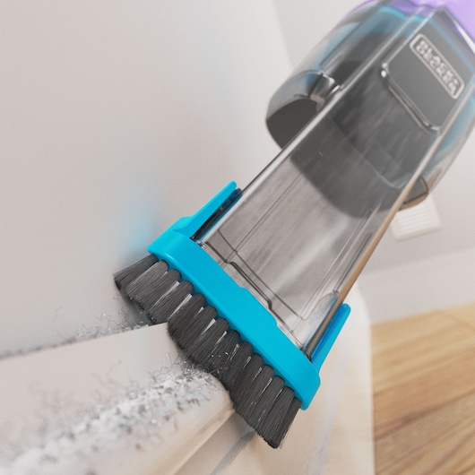 BLACKDECKER NVD220BP handstofzuiger met blauwe borstelmond reinigt stof van wit oppervlak, close-up.