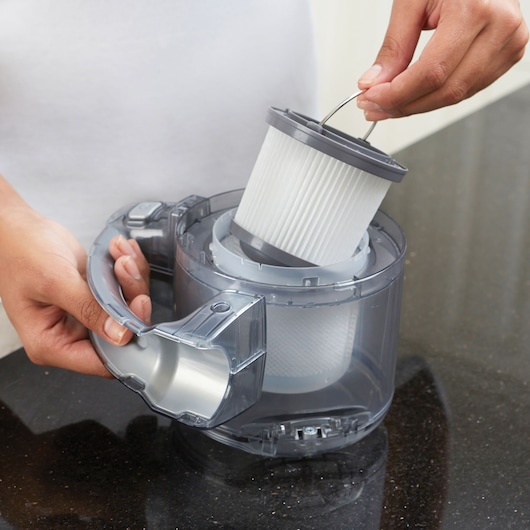 Filtre d’aspirateur BLACKDECKER PD1020L retiré du bac transparent sur un plan de travail sombre.