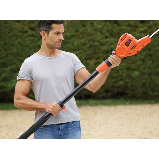 BLACKDECKER PH5551 telescopische heggenschaar met oranje behuizing en verstelbare zwarte steel, buiten vastgehouden.