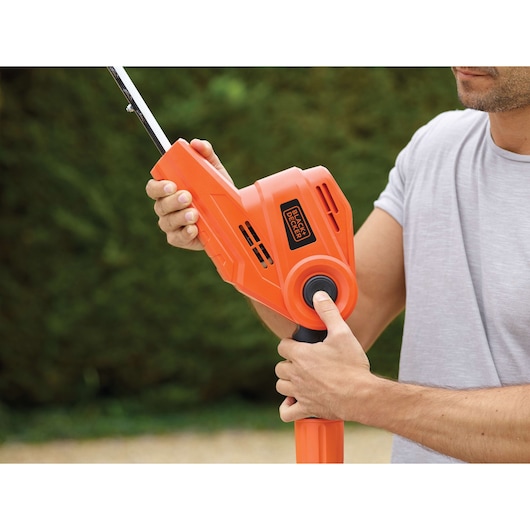 Oranje BLACKDECKER PH5551 heggenschaar handgreep vastgehouden door persoon buiten.