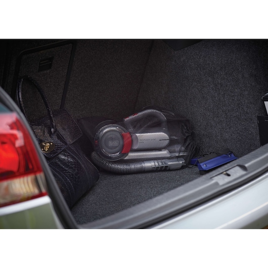BLACKDECKER PV1200AV aspirateur à main rangé dans le coffre d'une voiture, accessoires et sac visibles.
