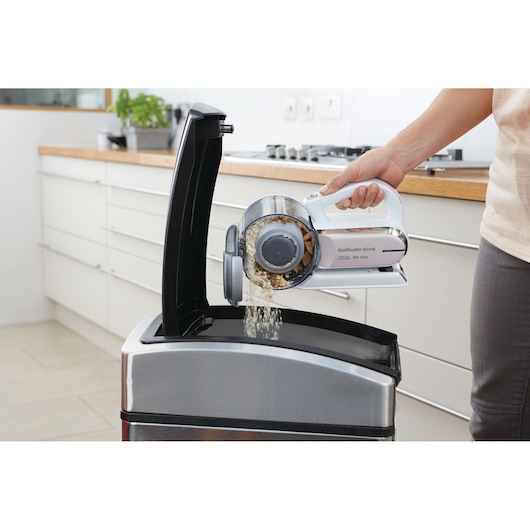 Aspirateur à main BLACKDECKER PV1820LRGP vidé dans une poubelle en acier dans une cuisine.