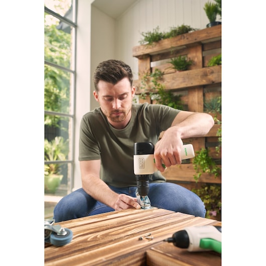 Photo de la perceuse sans fil BLACK+DECKER REVDD12C utilisée pour assembler un meuble en bois à l'intérieur.
