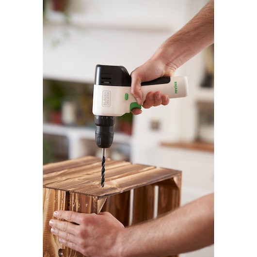 Photo d'une perceuse sans fil BLACK+DECKER REVDD12C utilisée pour percer une caisse en bois à l'intérieur.