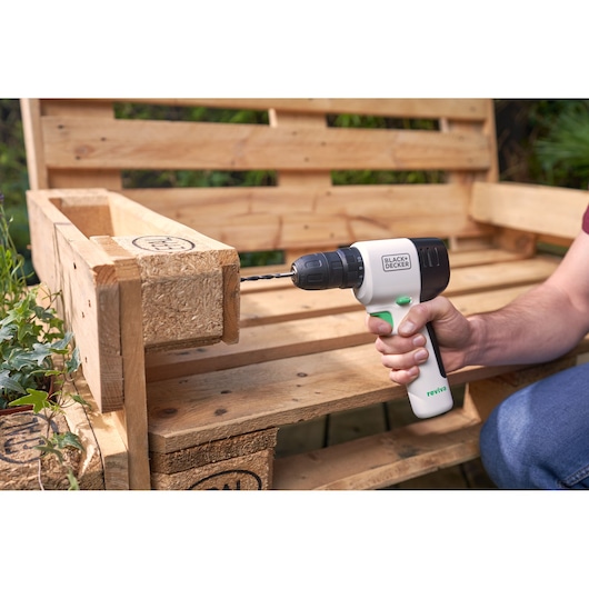 BLACKDECKER REVDD12C perceuse sans fil utilisée sur un banc en palette bois à l'extérieur.