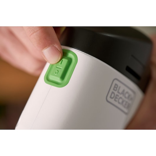 Photo en gros plan d'une main appuyant sur le bouton vert du BLACK+DECKER REVDS12C, logo visible.
