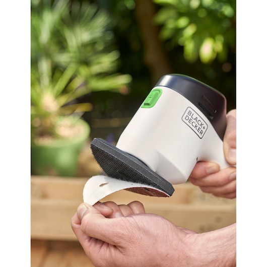 BLACK+DECKER REVDS12C ponceuse à main avec patin abrasif en milieu de jardin.