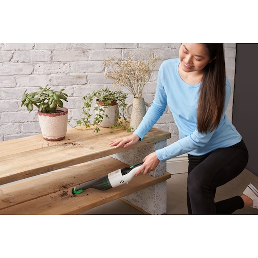 BLACKDECKER REVHV8C handstofzuiger verwijdert aarde van houten planken naast plantenpotten, binnenomgeving.