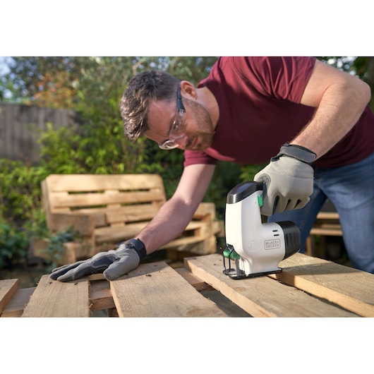 BLACKDECKER REVJ12C decoupeerzaag gebruikt op houten pallet buiten door persoon met handschoenen.
