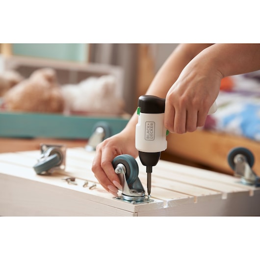 Photo du tournevis sans fil BLACKDECKER REVSD4C assemblant des roulettes sur une caisse en bois.