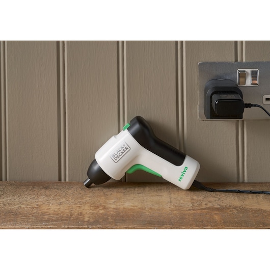 Tournevis sans fil BLACK+DECKER REVSD4C blanc et noir avec accents verts en charge sur une surface en bois.