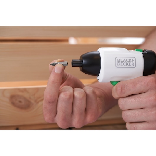 Gros plan sur le tournevis sans fil BLACK+DECKER REVSD4C avec une main tenant un embout près du bois.