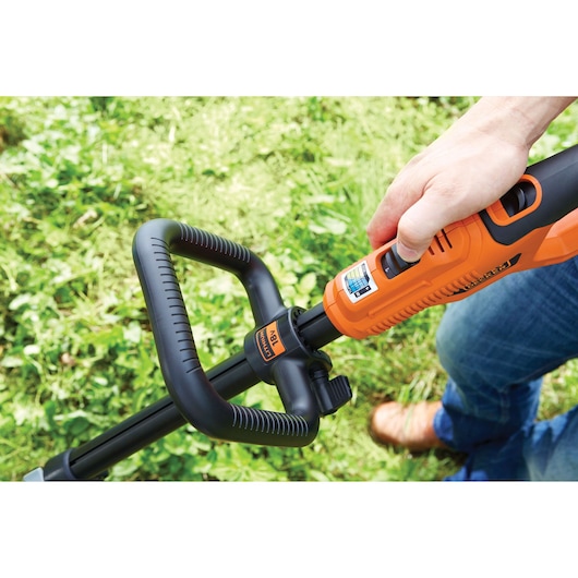 Photographie de la poignée coupe-bordures BLACKDECKER STC1840PC, orange et noir, en utilisation extérieure.