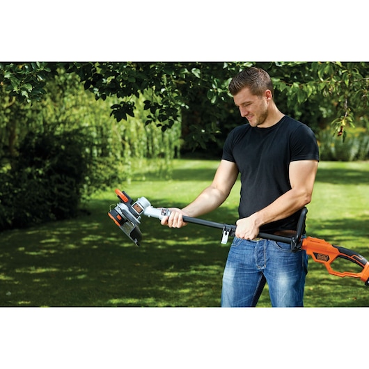 Photo du coupe-bordures BLACKDECKER STC1840PC utilisé en extérieur, design orange et noir, outil de jardin à main.