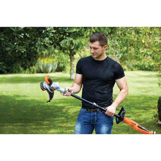 Photo d'une personne tenant un coupe-bordures sans fil BLACKDECKER STC1840PC dans un jardin.
