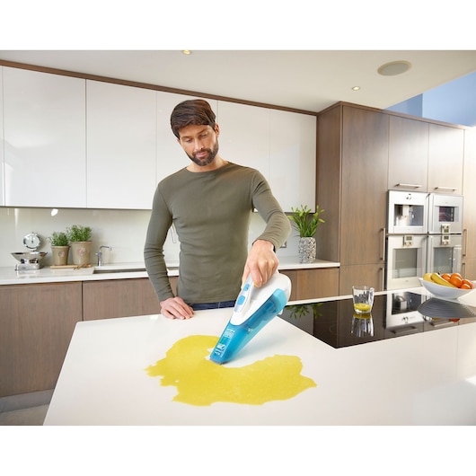 BLACKDECKER WDA315J aspirateur à main nettoyant une tache de liquide sur un plan de travail de cuisine.
