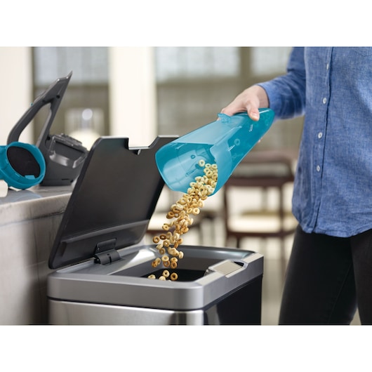 Foto van BLACKDECKER WDA320J handstofzuigerreservoir dat wordt geleegd in een afvalbak in de keuken.