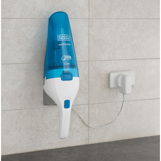 Foto van de BLACK+DECKER WDC115WA handstofzuiger met blauwe en witte behuizing, aan de muur gemonteerd en aan het opladen.